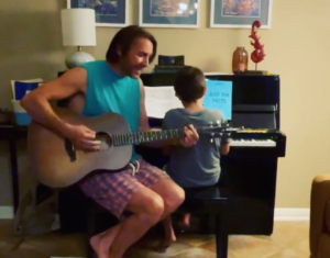 A father plays guitar while his son plays piano.