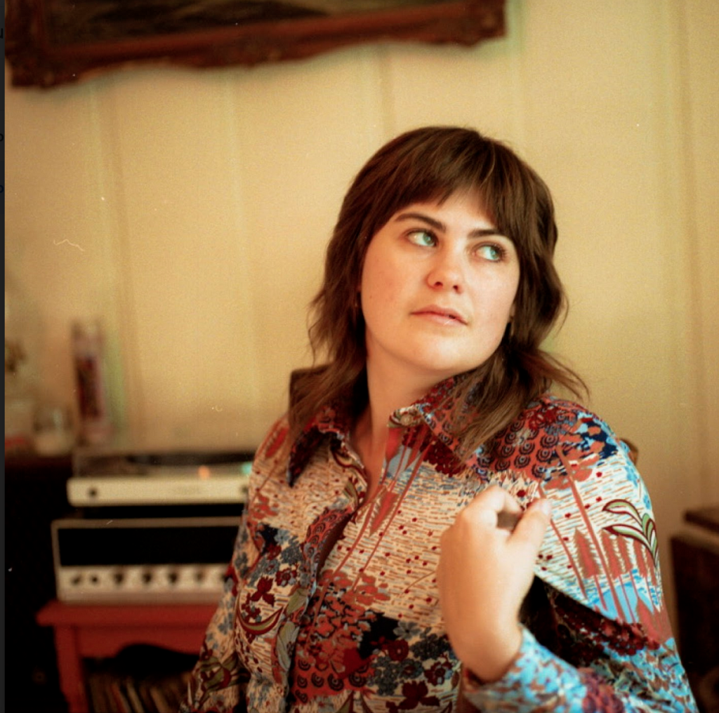 Photo of Jobi Riccio in a colorful vintage shirt sitting in front of a keyboard.