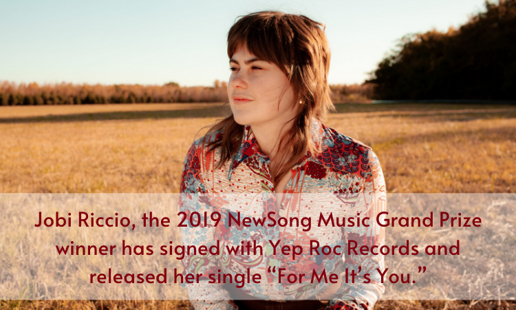 Singer-songwriter Jobi Riccio sits in a field.