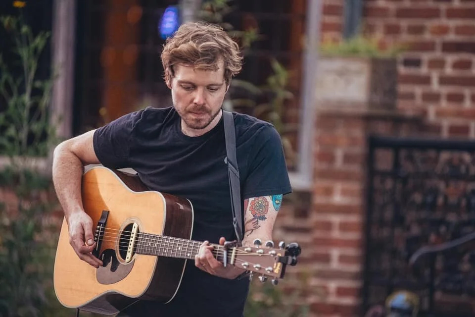 Singer-songwriter Logan Vath holds an acoustic guitar.